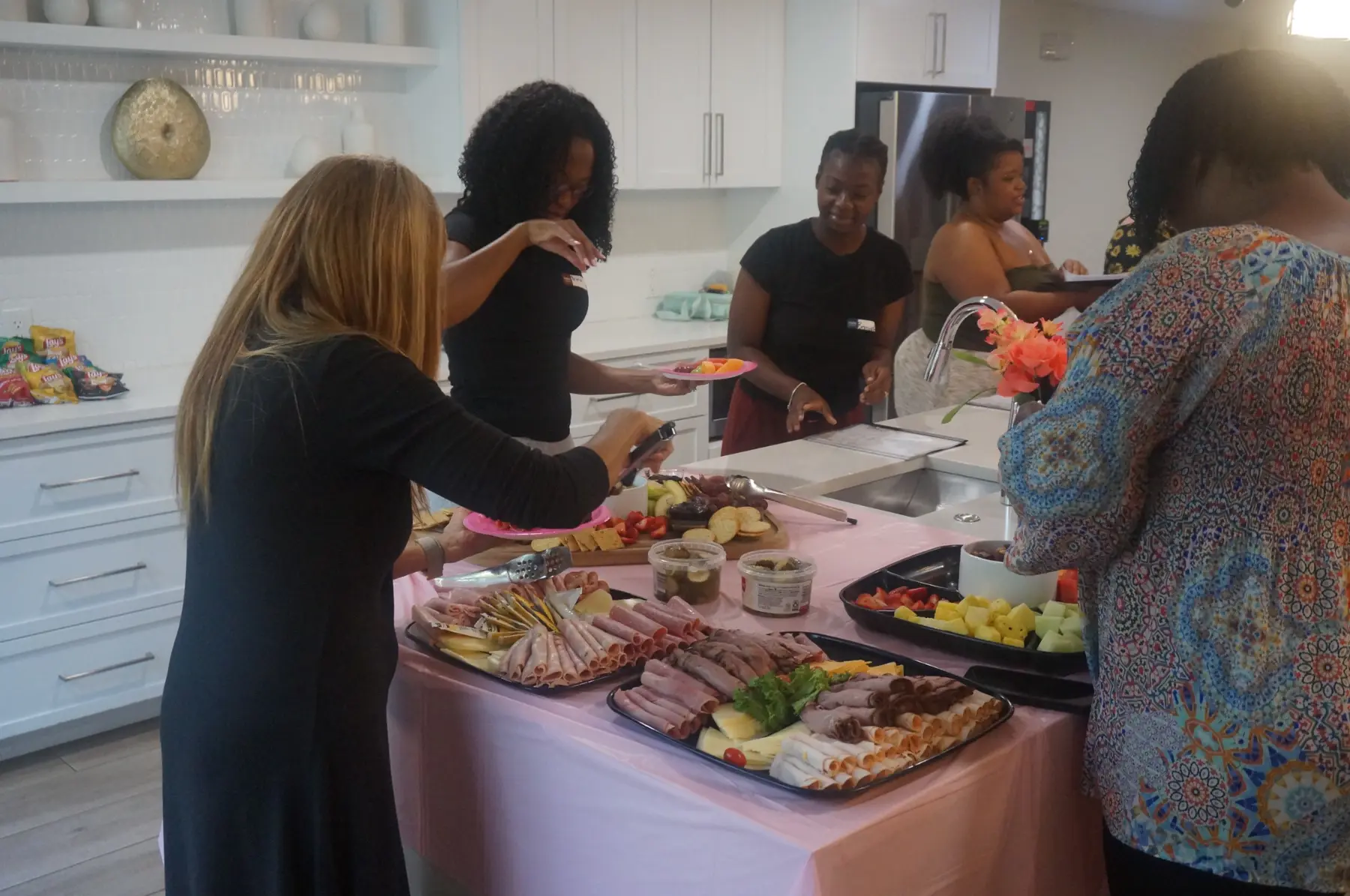 Women selecting food from the charcuterie spread