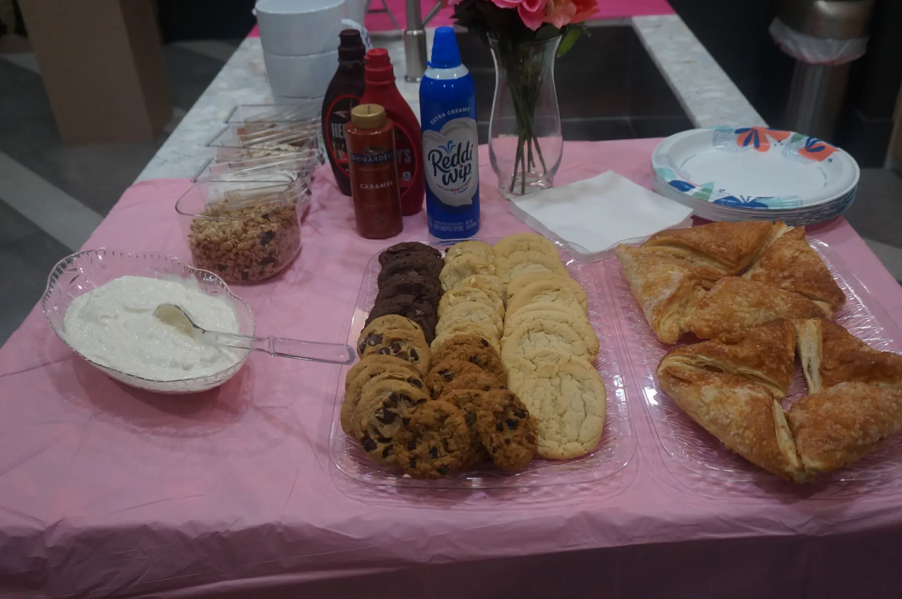 Cookies, pastries, whipped topping, and dessert sauces arranged on the table