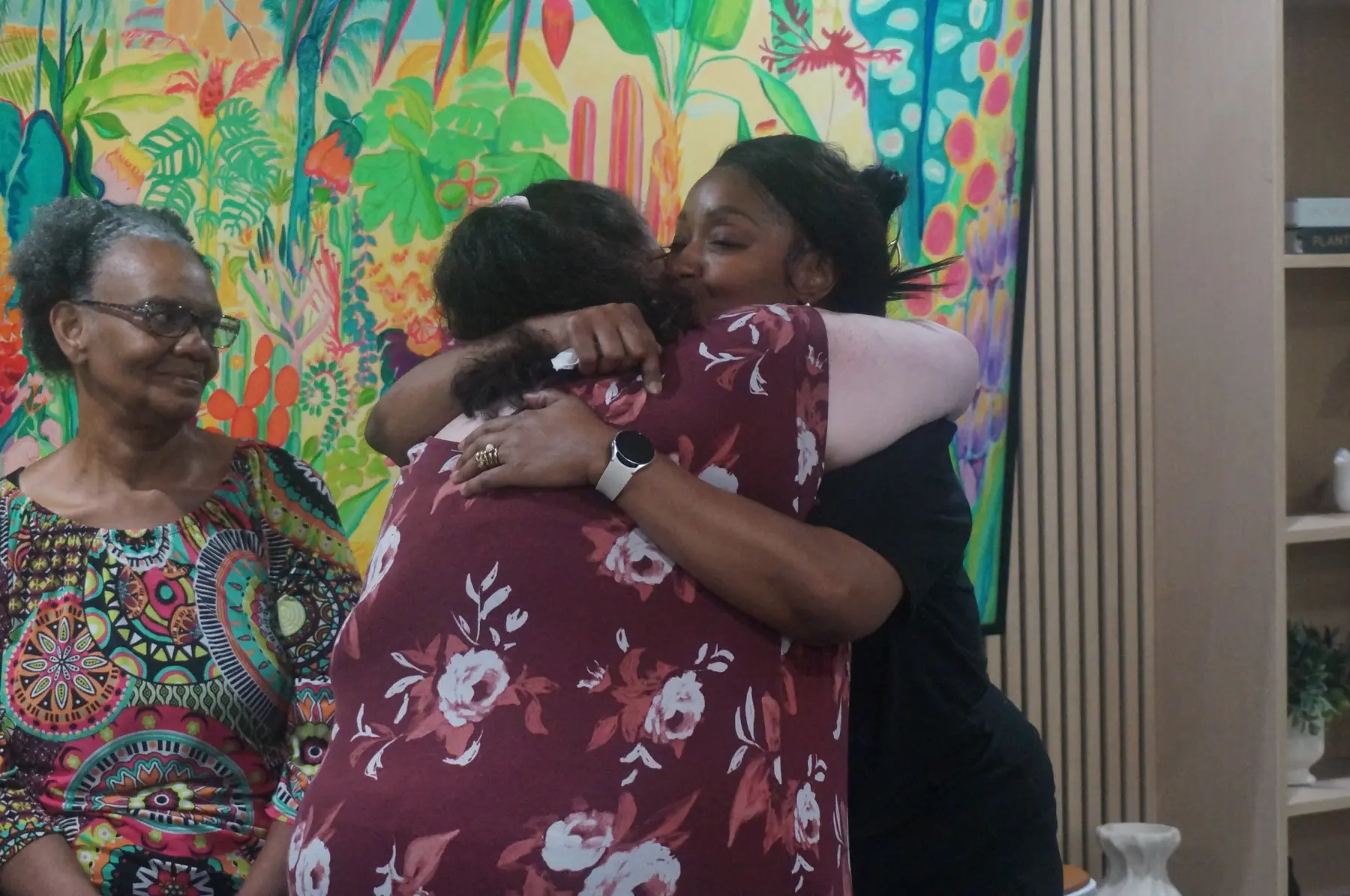 Two women embracing as others look on