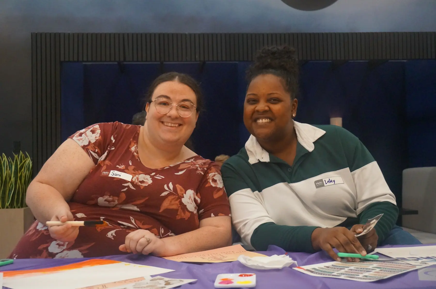 Two women smiling together while creating their boards