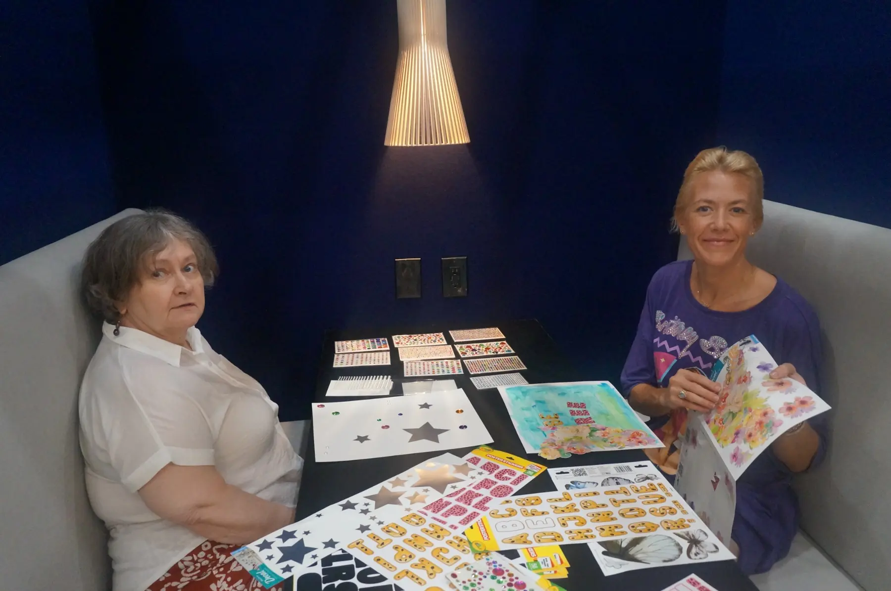 Two women holding their colorful vision-board creations